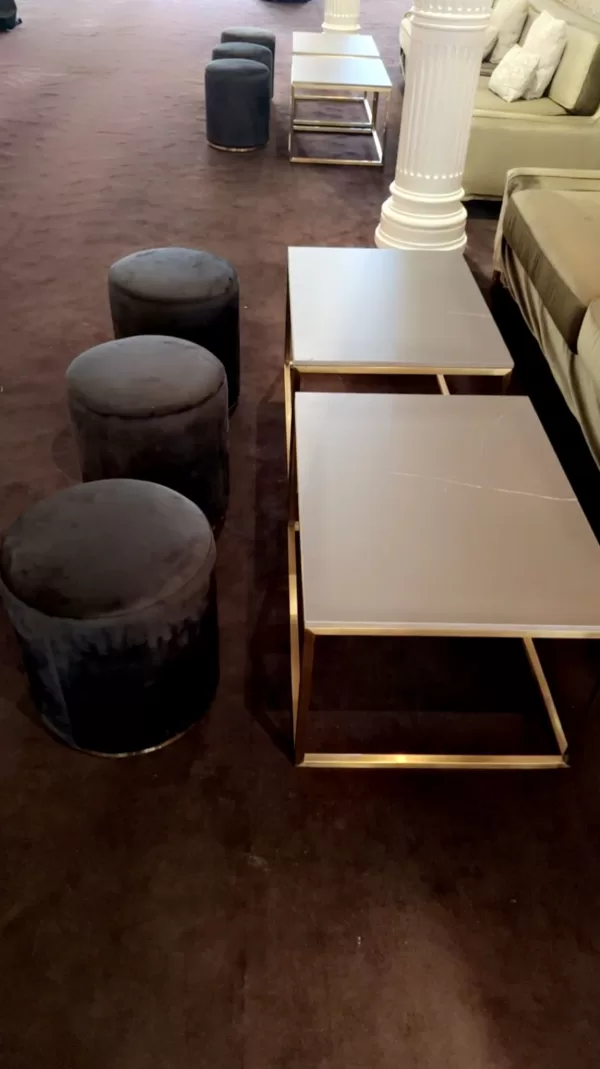 gold rectangular coffee table with black marble table top with black velvet ottoman stool at an event