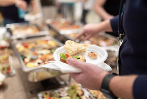 hand holding a plate full of food at a buffet